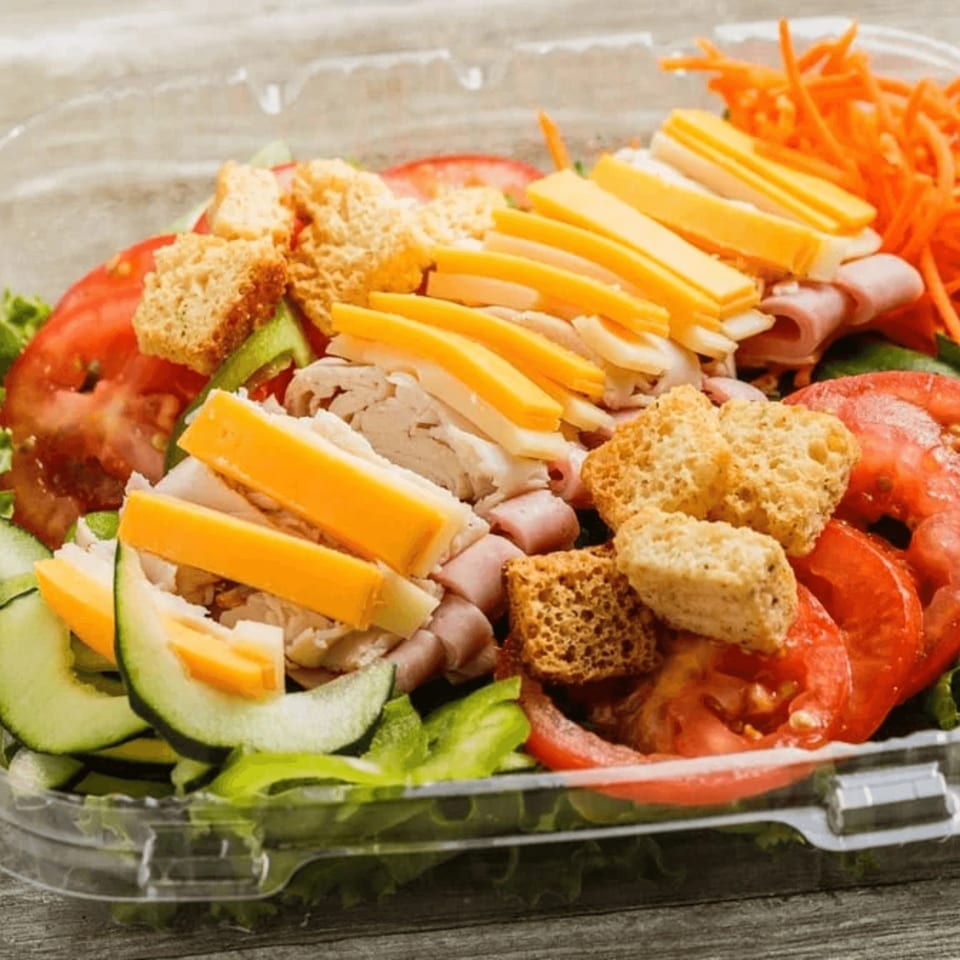 A Roly Poly chef salad with ham, turkey, cheese, croutons, tomatoes, cucumbers, and carrots.