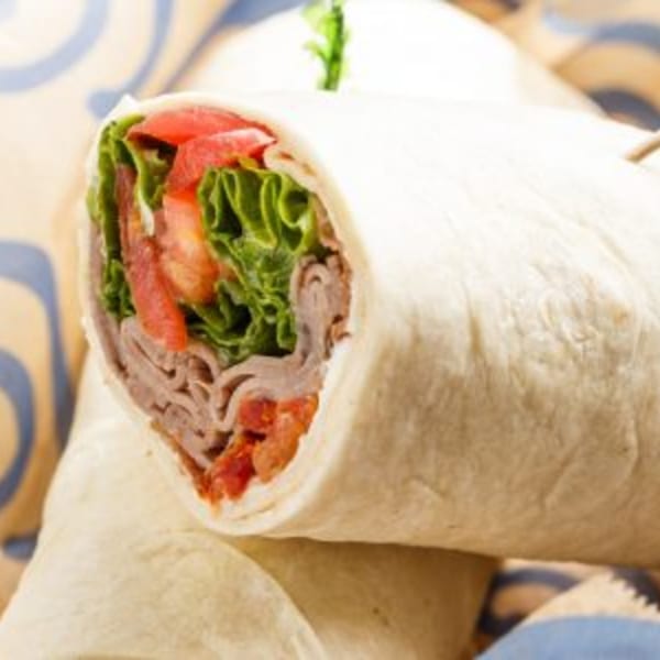 A Roly Poly roast beef wrap, filled with lettuce, tomatoes, and thinly sliced meat.