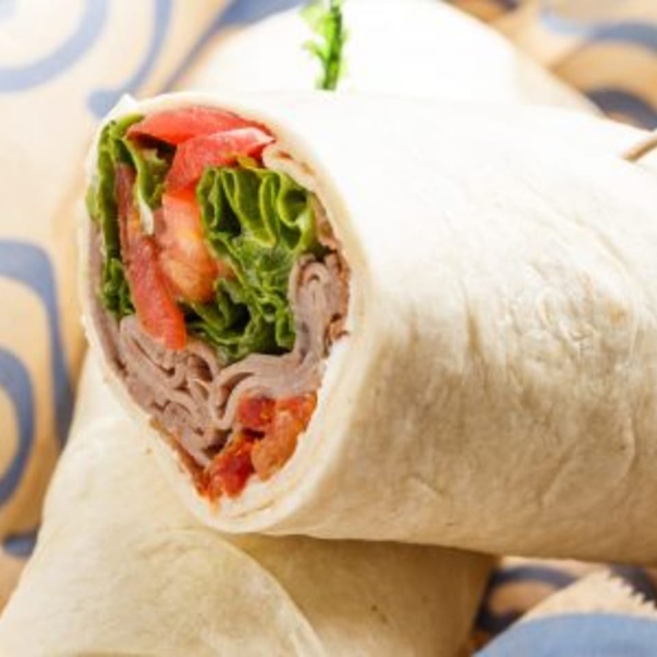 A Roly Poly roast beef wrap, filled with lettuce, tomatoes, and thinly sliced meat.