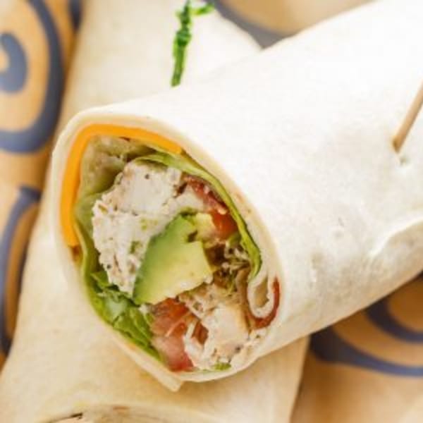 Roly Poly chicken salad wrap with avocado, lettuce, tomato, and cheese, held by a toothpick.