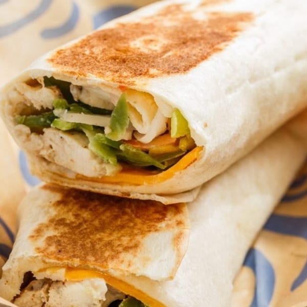 Two Roly Poly chicken wraps, filled with cheese, lettuce, and other vegetables.